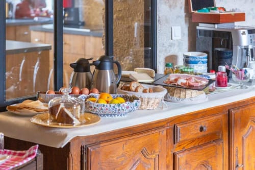Breakfast buffet spread at Les logis de Kergoulou B&B in Concarneau with pastries, fruit, eggs, and charcuterie on wooden