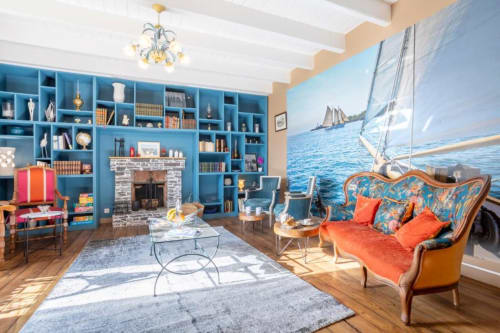 Elegant blue-shelved living room with ornate sofa, fireplace, and sailboat art at Les logis de Kergoulou, Concarneau