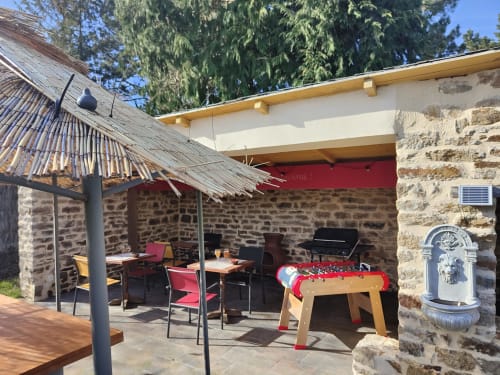Outdoor patio at Les logis de Kergoulou with foosball table, dining seating, and stone architecture in Concarneau