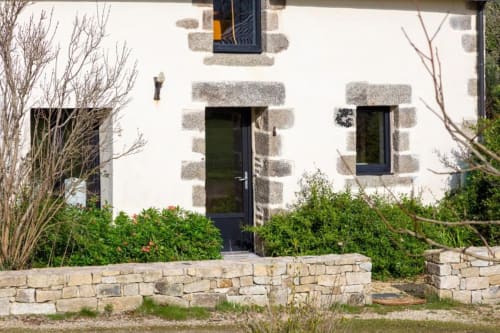 Les logis de Kergoulou BnB in Concarneau with whitewashed stone facade, dark door, and landscaped garden