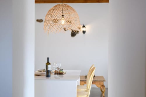 Modern dining area at Finca de La Geria with woven pendant lamp, wine bottle, and wooden chair