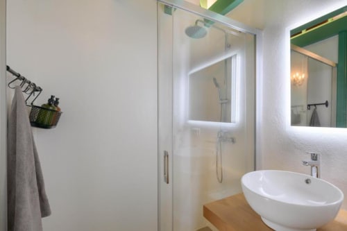 Modern bathroom at Finca de La Geria cottage with round white sink, illuminated mirror, and glass-enclosed shower with