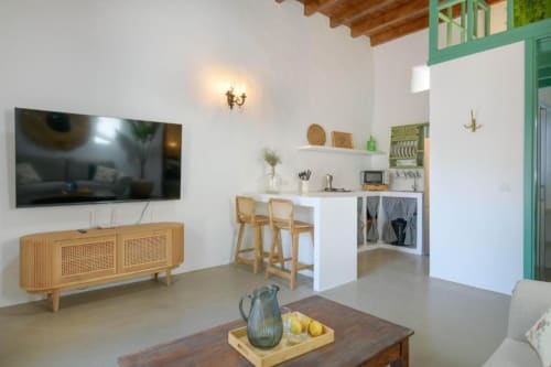 Modern cottage living area at Finca de La Geria with kitchen, dining seating, TV, wooden furniture and garden views