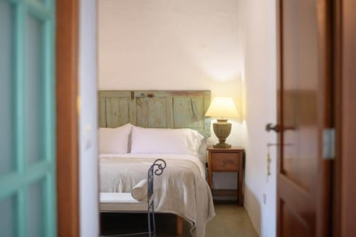 La Era cottage bedroom at Finca de La Geria with wooden headboard, white bedding, and garden views in Yaiza
