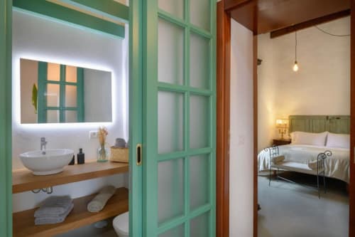 La Era cottage bathroom with illuminated mirror, vessel sink, and view into bedroom at Finca de La Geria, Yaiza