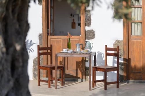 Outdoor dining area at Finca de La Geria with wooden chairs, table, and rustic stone architecture in Yaiza