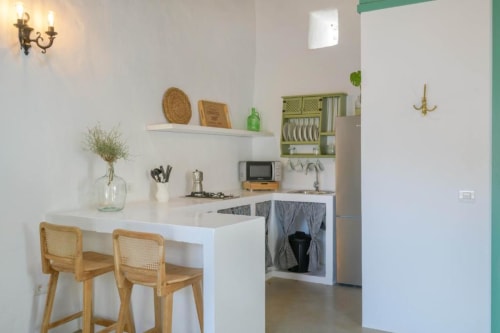 Modern cottage kitchen at Finca de La Geria with white counter, wooden stools, green cabinets, and garden views