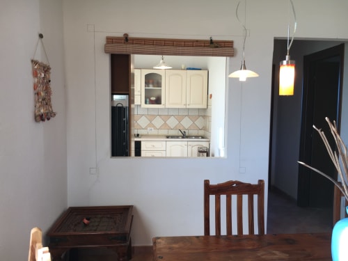 Kitchen pass-through window in Domo Giulia villa, Orosei, showing cream cabinetry and dining area