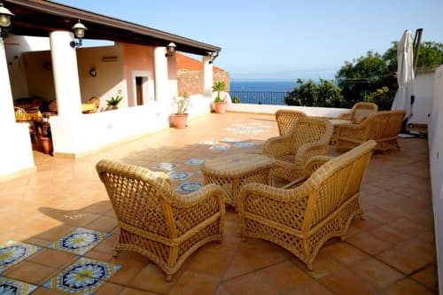 Ampia terrazza dell'Hotel Principe di Rinella con sedute in vimini, vista mare e arredamento mediterraneo a Rinella, Italia