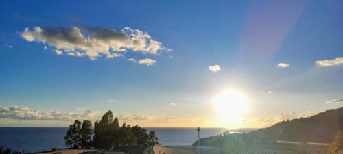 Tramonto sul Mar Mediterraneo dall'Hotel Principe di Rinella a Rinella, Italia, con scogliere costiere e barca a vela