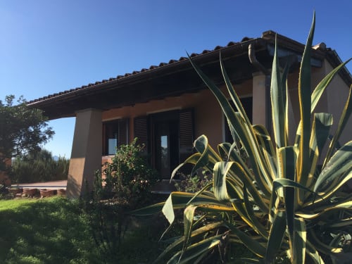 Domo Giulia villa in Orosei with terracotta-tiled porch, wooden furniture, and agave plants
