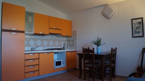 Orange kitchen with blue countertops and dining area in Orosei villa with sea view accommodation