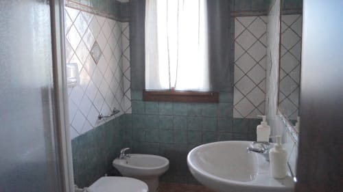 Bathroom in Domo Sara villa, Orosei featuring sink, bidet, tiled walls, window and shower