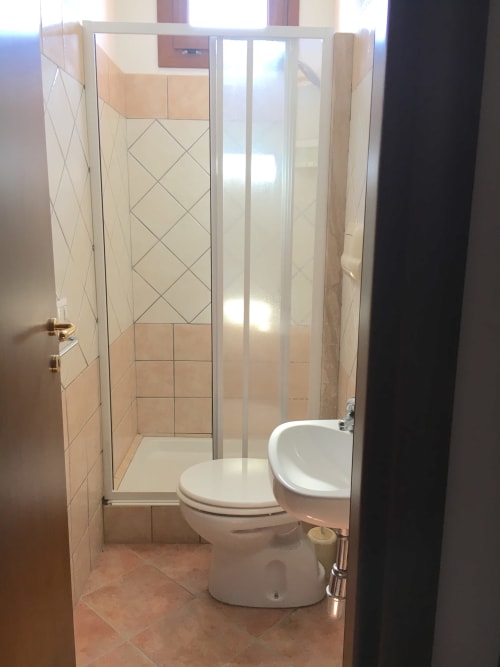 Modern bathroom in Domo Sara villa with shower enclosure, toilet, and sink in Orosei