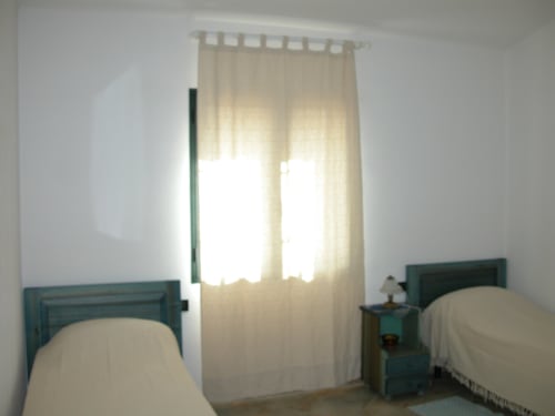 Bright bedroom with twin beds and teal headboards, sea-view villa in Orosei, Italy