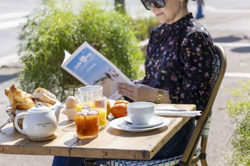 Femme lisant le menu à la table d'un café en plein air avec petit-déjeuner à l'Hôtel De Lion Sur Mer