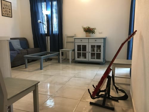 Modern villa living room in Orosei with teal furniture, tiled floors, blue curtains, and musical instrument display