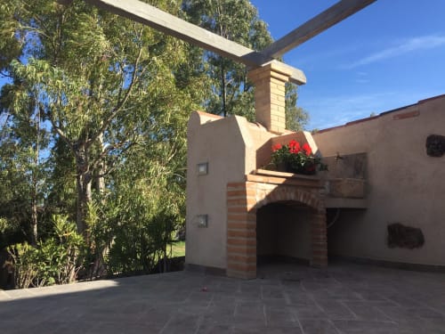 Terrazza della villa Sa Domo De Mannoi a Orosei con arco in laterizio, fiori rossi, pergolato in legno e alberi di eucalipto