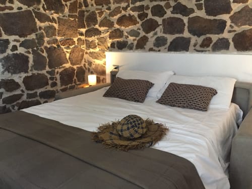Camera da letto in pietra rustica a Sa Domo De Mannoi a Orosei con biancheria bianca, cuscini decorati e arredamento tradizionale