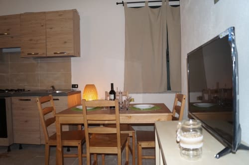Modern kitchen and dining area with wooden furnishings, flat-screen TV, and beige curtains in Villa Sa Tanca De Mannoi,