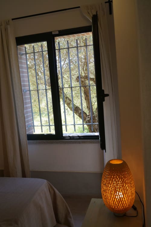 Modern villa bedroom at Loddo Paola with garden view through barred windows and ambient orange lamp lighting