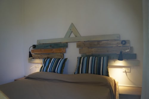 Rustic wooden pallet headboard with striped pillows and warm bedside lighting in Sa Tanca De Mannoi villa