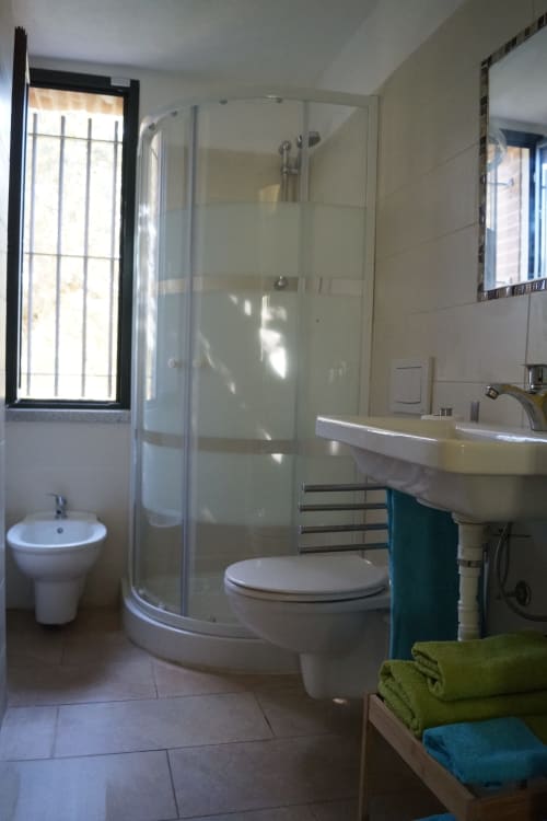 Modern bathroom in Sa Tanca De Mannoi villa, Orosei with shower, toilet, sink and green towels
