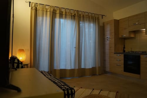 Modern villa interior in Orosei with kitchen, large windows, curtains, and contemporary furnishings
