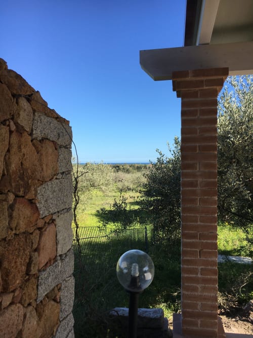 Coastal garden view from Sa Tanca De Mannoi villa in Orosei with Mediterranean vegetation and sea horizon