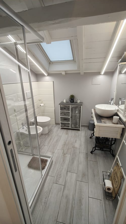 Bagno moderno nel loft TuffonelBlu di Ventimiglia: lucernario, doccia, lavabo tondo e pavimenti effetto legno