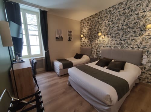 Triple bedroom at Le Pavillon Saint Martin Hotel in Souillac with two beds, patterned wallpaper, and city view window