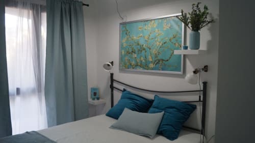 Modern bedroom in Orosei apartment with blue accents, metal bed frame, Van Gogh almond blossoms artwork, and turquoise