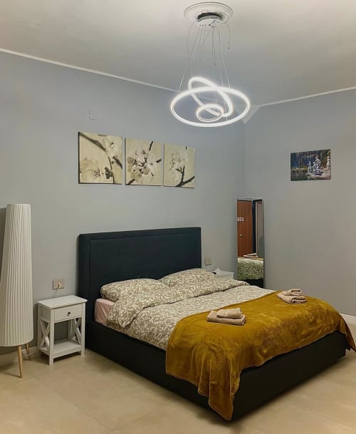 Camera moderna della San Carlo 104 B&B a Caserta con letto nero, lampadario neon contemporaneo e vista sulla città