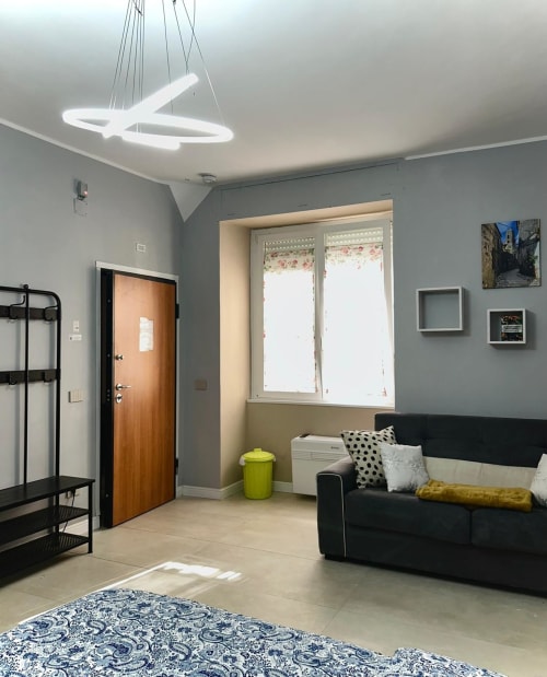 Stanza 101 del San Carlo 104 B&B a Caserta con divano nero, lampada a sospensione moderna e vista sulla città