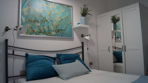 Modern bedroom in Orosei apartment with turquoise Van Gogh art, black metal bed frame, and white wardrobe closet