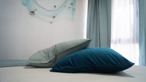 Blue and gray decorative pillows on a bed in Domo e' Chelu apartment, Orosei with city view windows