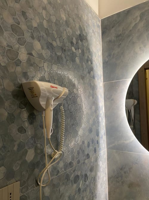 Asciugacapelli beige a parete su piastrelle in pietra testurizzata nel bagno della camera San Carlo 104, hotel Caserta