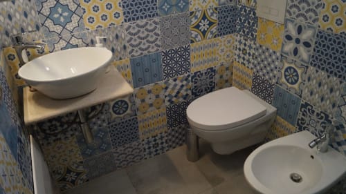 Colorful patterned bathroom in Orosei apartment with vessel sink, wall-mounted toilet, and bidet fixtures