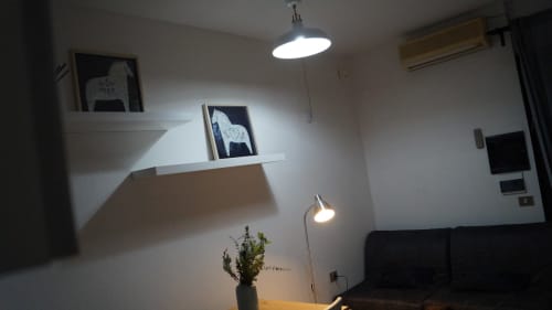 Modern apartment living room in Orosei with pendant lighting, wall shelves displaying artwork, and black sofa