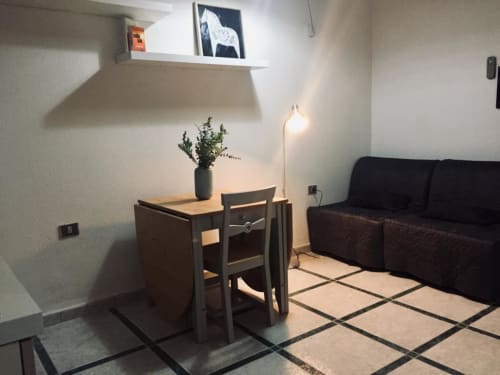 Cozy apartment living room in Orosei with black sofa, wooden dining table, and modern floor lamp