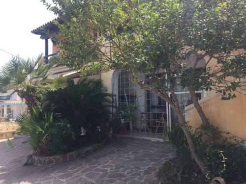Charming Orosei apartment entrance with lush greenery, terracotta walls, and shaded veranda patio area