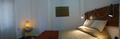 Cozy bedroom in Orosei apartment with warm lighting, wooden bed frame, striped pillows, and ambient lamps