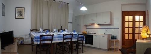 Modern kitchen and dining area in Sa Domo De Mannoi apartment, Orosei Italy, with blue checkered table setting and