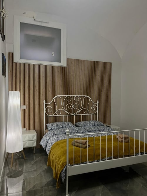 Camera moderna del San Carlo 104 B&B a Caserta con letto in metallo bianco, testata in doghe di legno e biancheria gialla