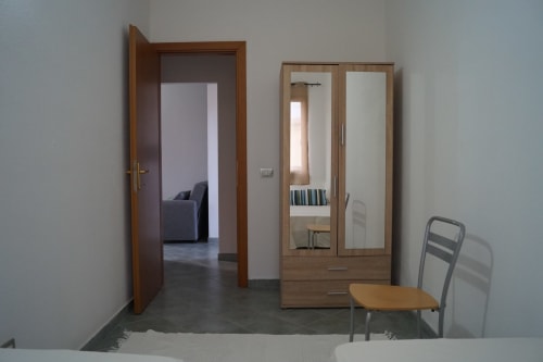 Wohnungseingang mit Holztür, Spiegelschrank und Stuhl in Orosei, Italien