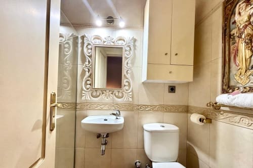 Baño lujoso en apartamento de Baiona con espejo ornamental, acabados modernos y azulejos color beige