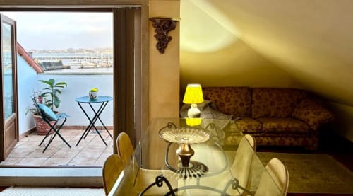 Apartamento en Baiona con vistas al mar, salón amueblado con sofá, lámpara amarilla, mesa de comedor y acceso a terraza frente al mar
