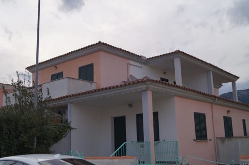 Zweistöckiges Apartment in Koralle und Weiß mit Terrasse in Orosei, mit Fensterläden und grünem Eingangstor