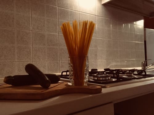 Kitchen countertop with pasta in glass holder, rolling pin, and gas stove at Loddo Paola apartment in Orosei