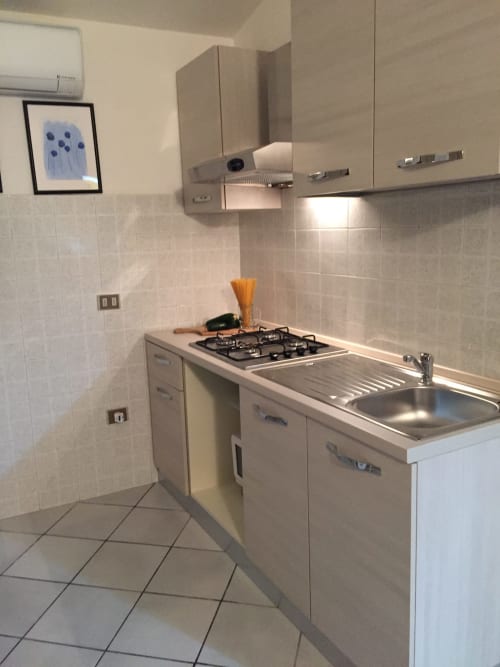 Modern compact kitchen in Casa Arborea B apartment, Orosei, with gas stove, sink, and white cabinetry